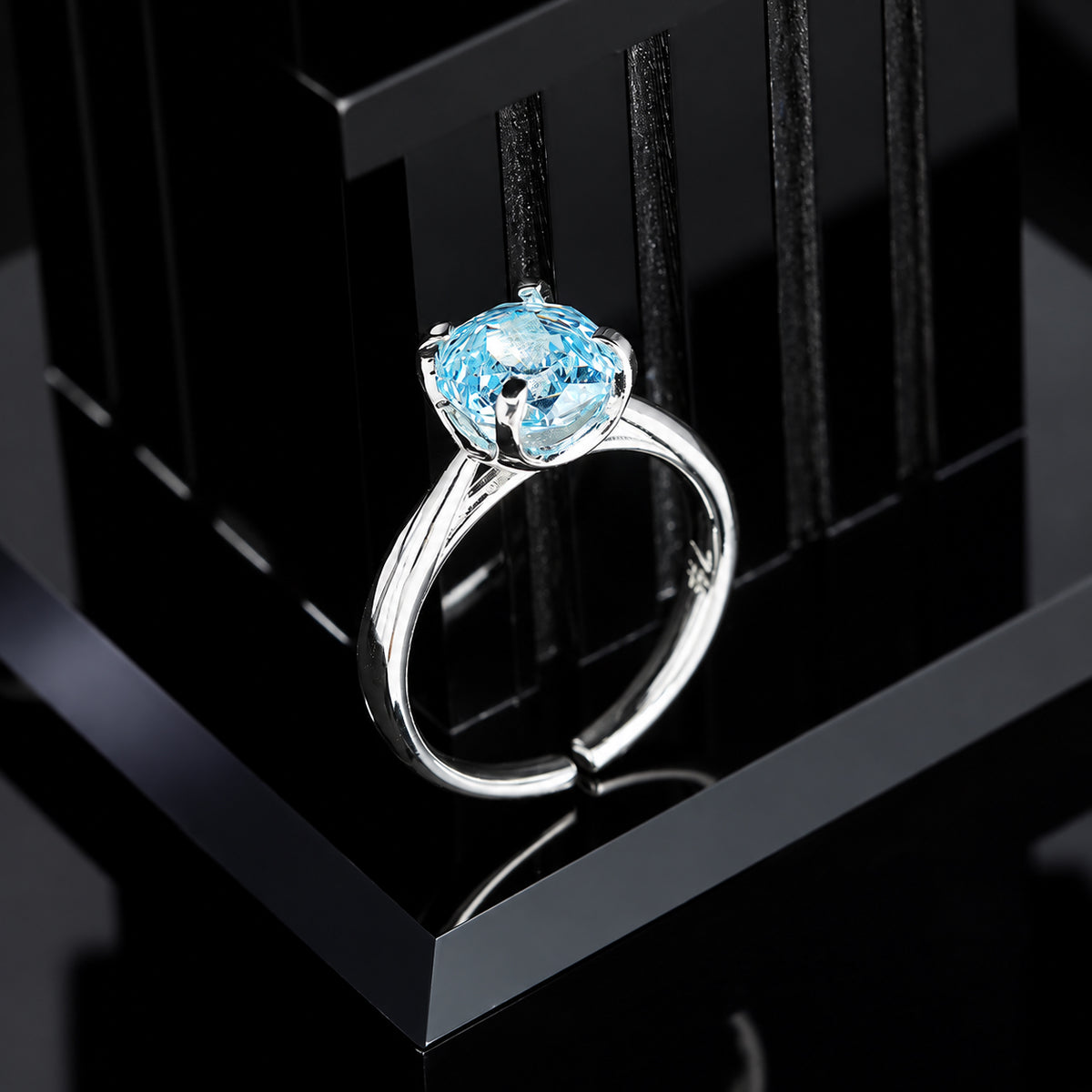 Single 8mm glacier blue round cubic zirconia solitaire ring in four-prong silver setting on black display