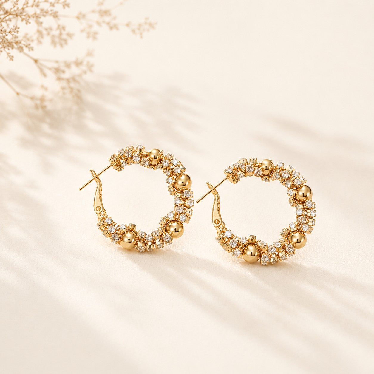 Flatlay view of pair of 2.8cm gold plated bubble bead and pave cz cluster hoop earrings