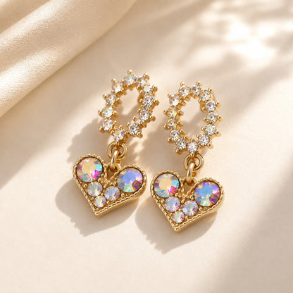 Pair of gold iridescent CZ crystal heart dangle earrings with oval halo studs on beige silk