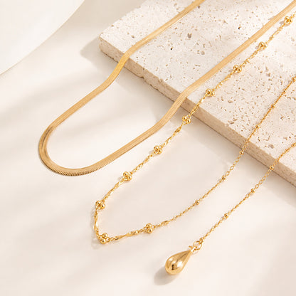 Close up of gold snake chain beaded strand and teardrop pendant necklace set