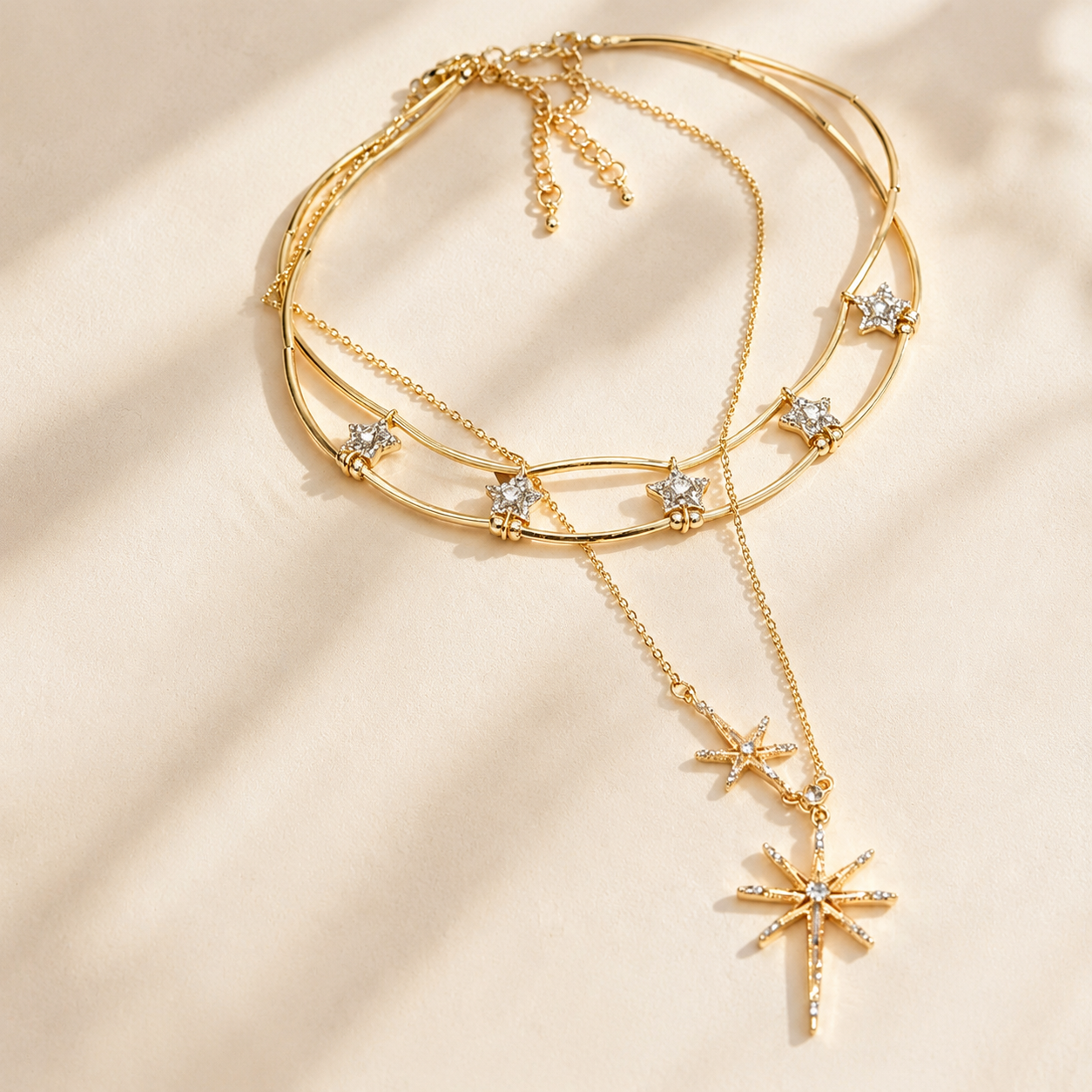 Detailed close-up of a sparkling gold-tone layered starburst necklace resting gracefully in warm, natural sunlight.