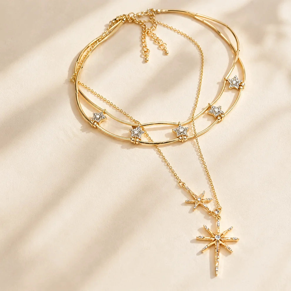 Detailed close-up of a sparkling gold-tone layered starburst necklace resting gracefully in warm, natural sunlight.