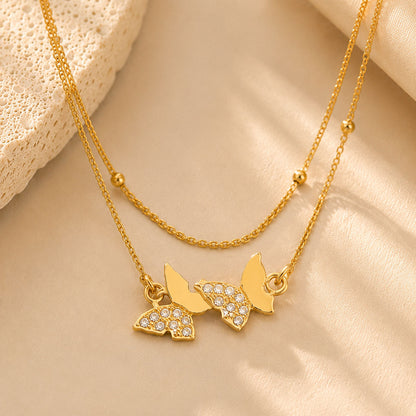 Close up macro detail of sparkling zirconia butterfly charms on a delicate double-layer gold-tone chain.