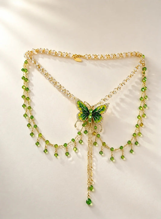 The wall hanging a layered necklace, showcasing a vibrant green butterfly pendant with cascading crystal tassels against a clean textured background in natural daylight.