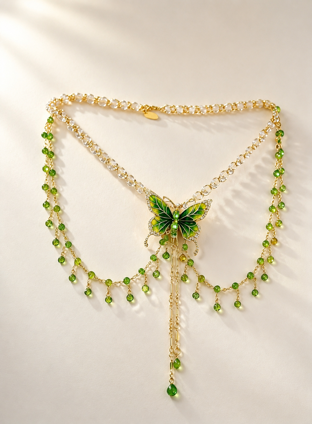 The wall hanging a layered necklace, showcasing a vibrant green butterfly pendant with cascading crystal tassels against a clean textured background in natural daylight.