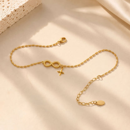 Elegant gold-tone infinity anklet resting on textured stone and soft silk in warm everyday light.