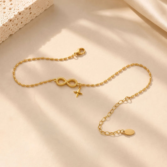 Elegant gold-tone infinity anklet resting on textured stone and soft silk in warm everyday light.