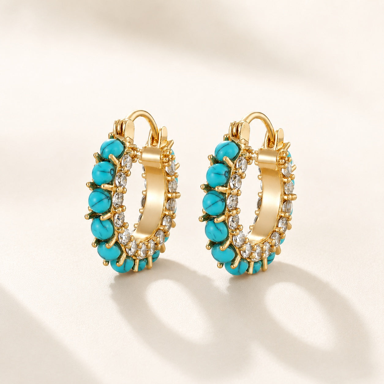 Flatlay view of pair of 2cm gold plated turquoise bead and pave cz hoop earrings
