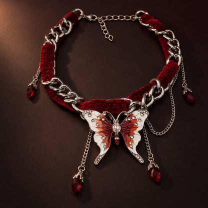 Gothic crimson red velvet choker intertwined with silver chain and enamel butterfly pendant on dark background