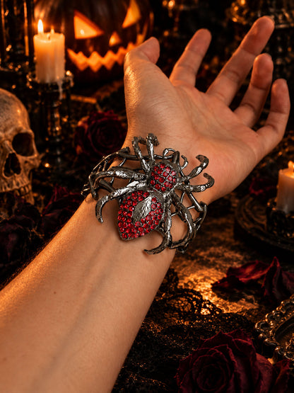 Close-up of model wrist displaying gothic crimson rhinestone spider bangle in Halloween candlelit setting