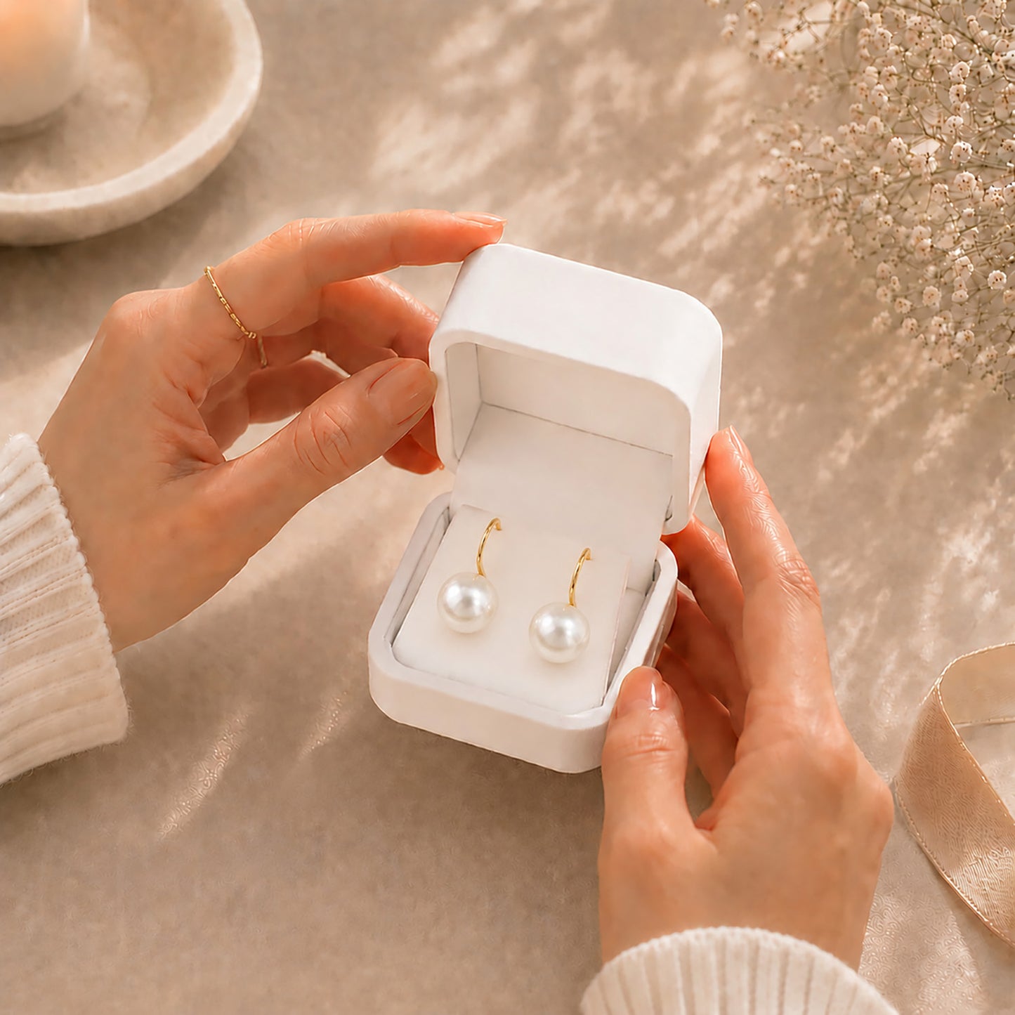 Hands gently opening a premium white Moonlook jewelry box revealing stunning 14K gold-plated oversized pearl earrings.