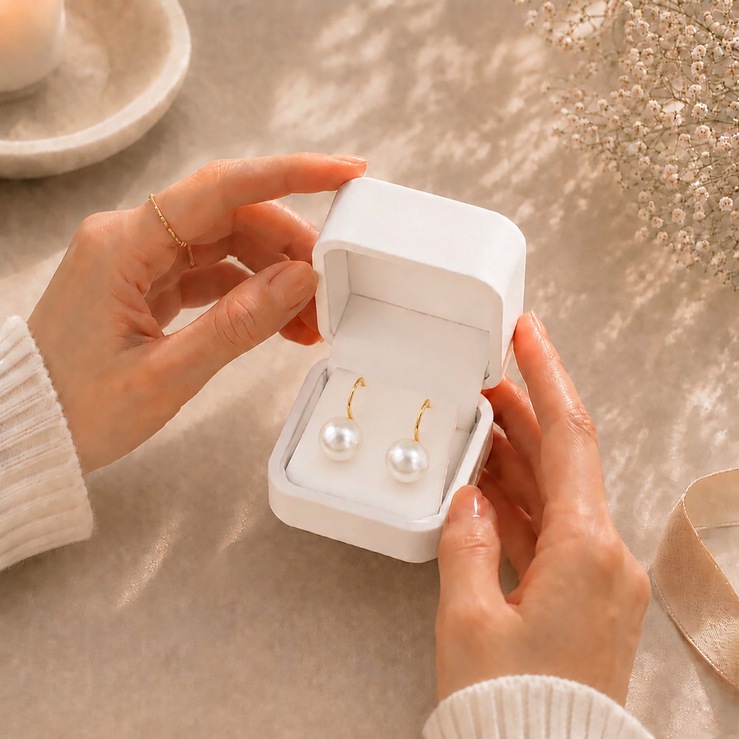 Hands gently opening a premium white Moonlook jewelry box revealing stunning 14K gold-plated oversized pearl earrings.