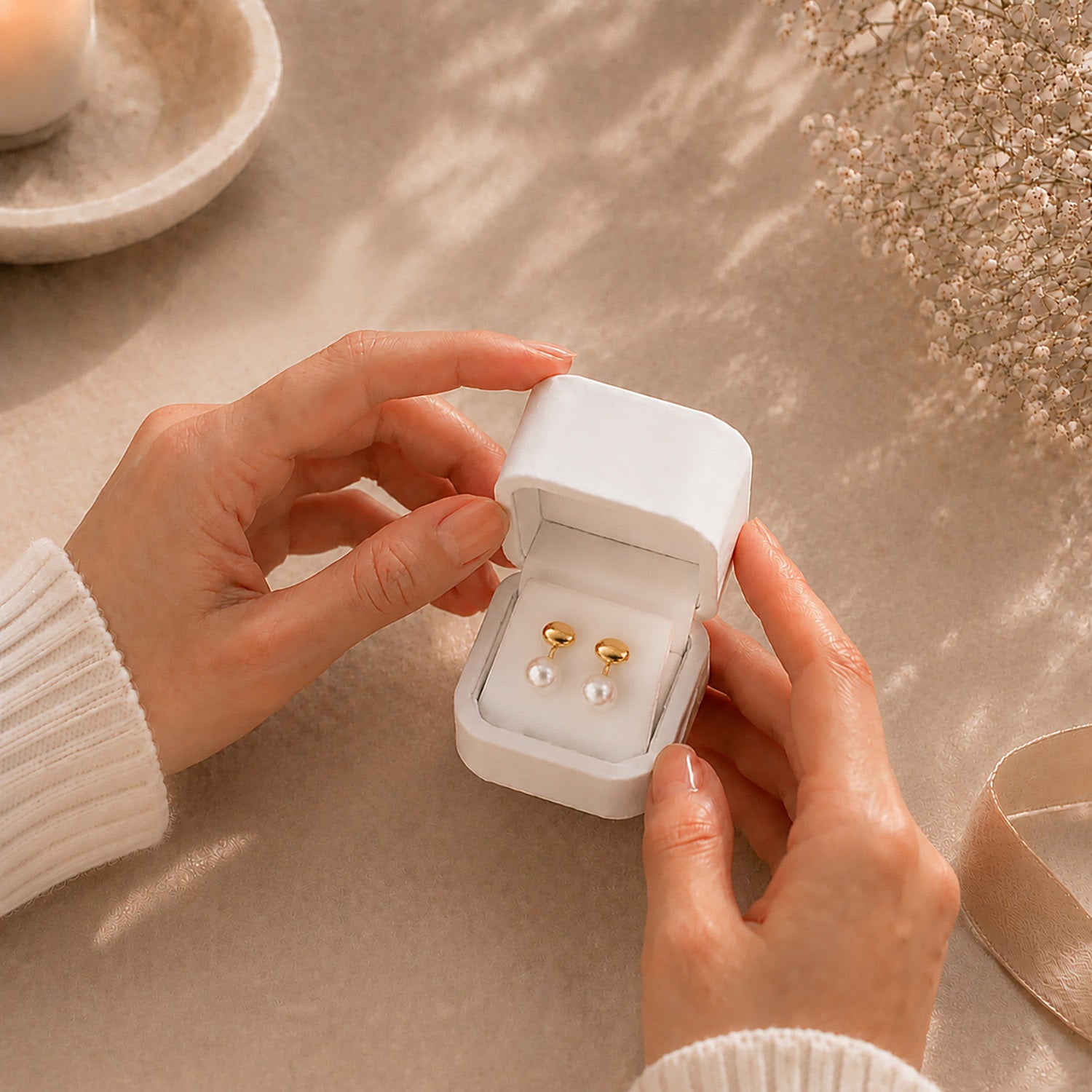 Hands gently opening a premium white Moonlook jewelry box revealing delicate gold and pearl jacket earrings.