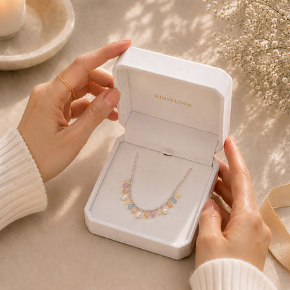 Hands opening a premium white Moonlook jewelry box revealing a sparkling rainbow zirconia necklace.