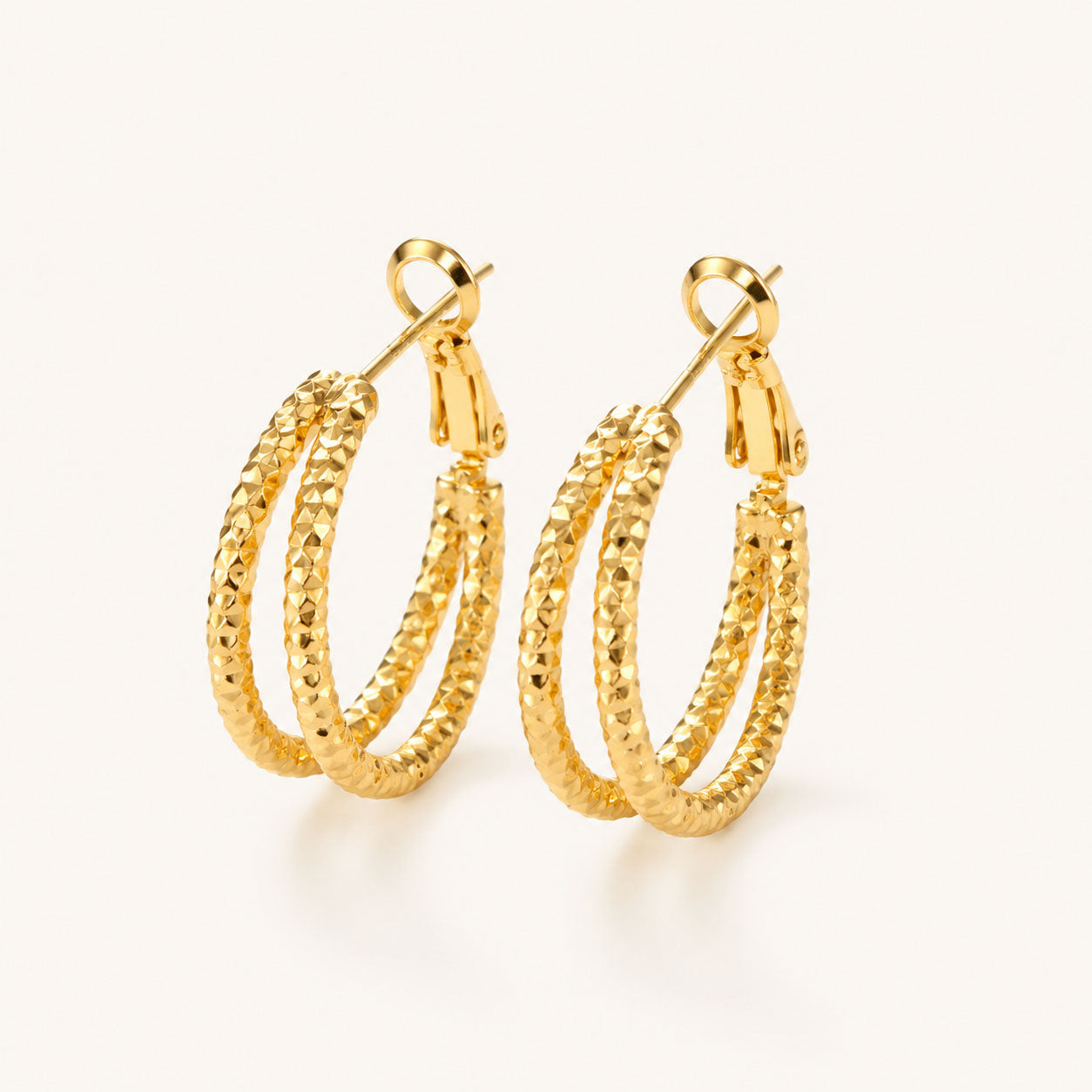 Minimalist textured double hoop earrings in a radiant gold-tone on a white background.