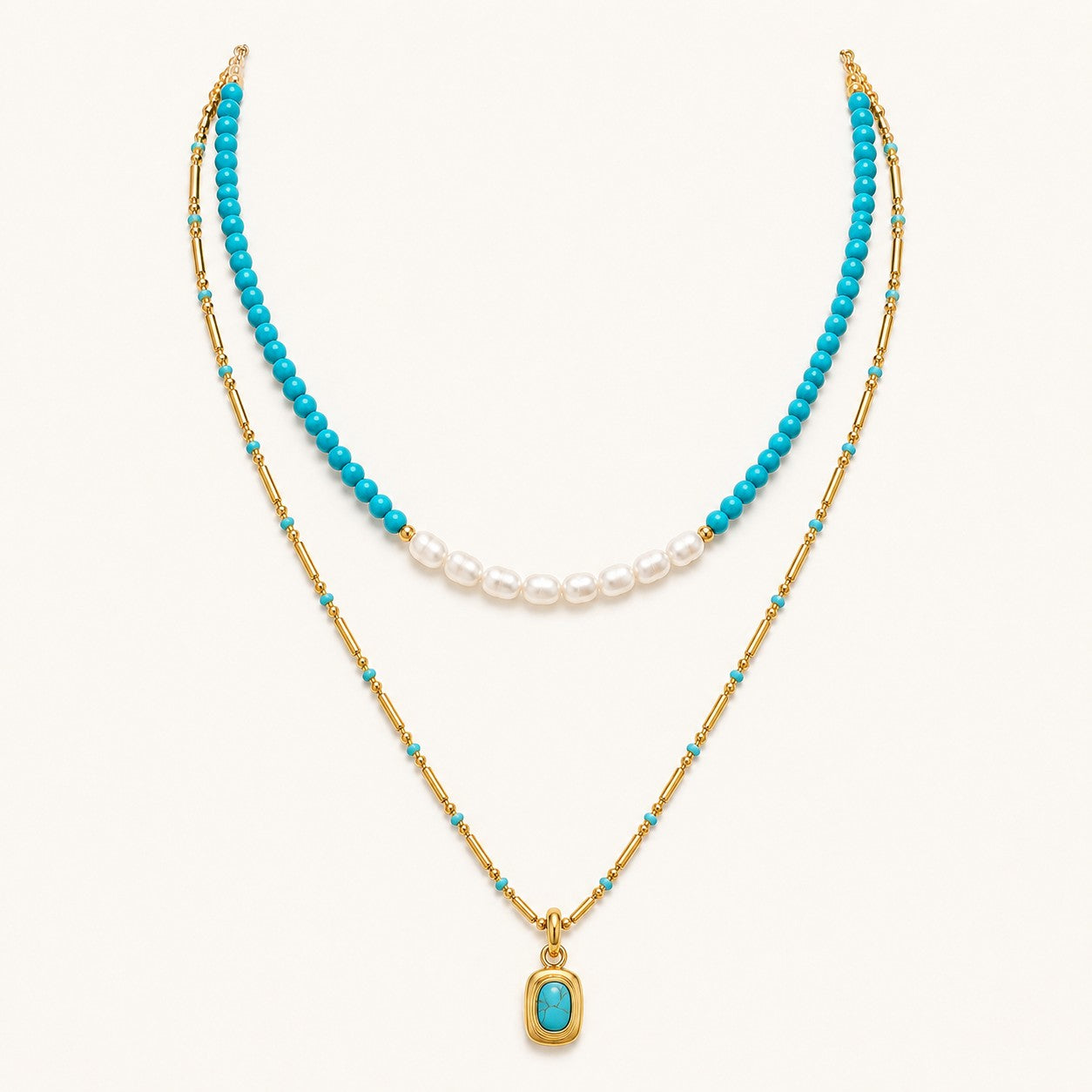 Layered turquoise and pearl necklace with gold chain and pendant on white background