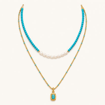Layered turquoise and pearl necklace with gold chain and pendant on white background