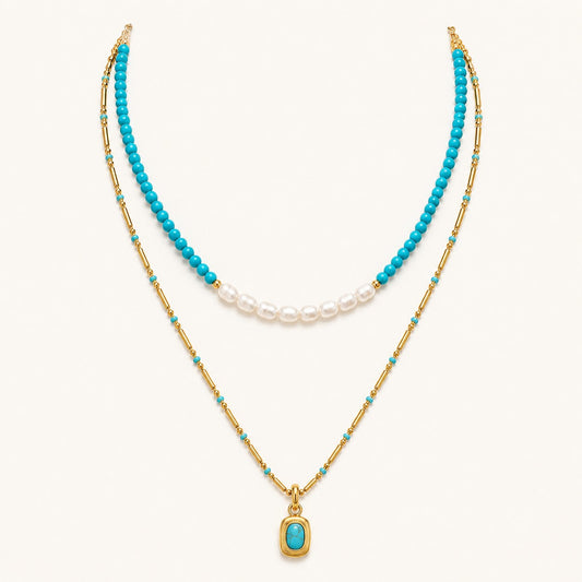 Layered turquoise and pearl necklace with gold chain and pendant on white background