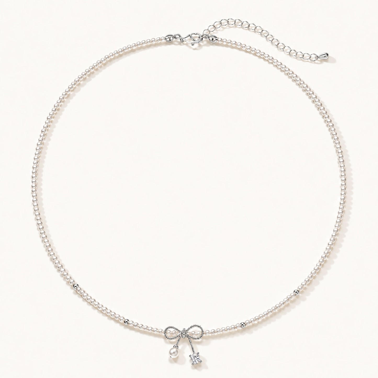 Minimalist white gold-tone pearl necklace featuring a dainty bowknot and zirconia drop on a clean white background.