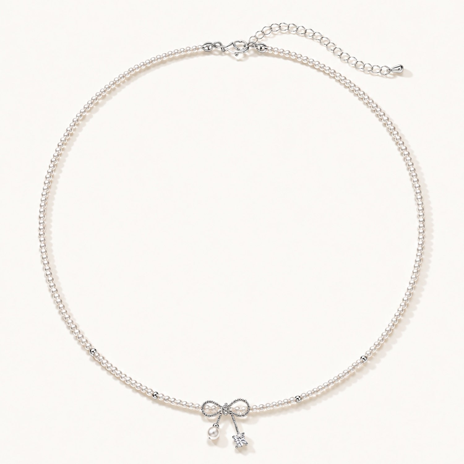 Minimalist white gold-tone pearl necklace featuring a dainty bowknot and zirconia drop on a clean white background.