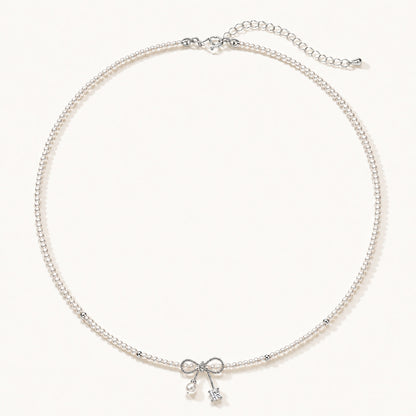 Minimalist white gold-tone pearl necklace featuring a dainty bowknot and zirconia drop on a clean white background.