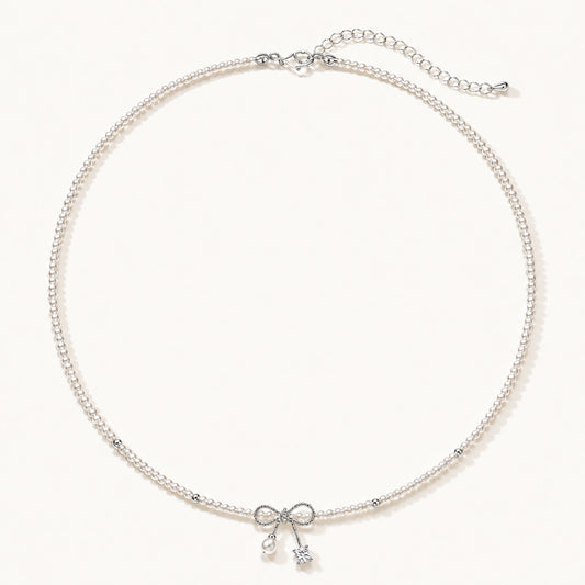 Minimalist white gold-tone pearl necklace featuring a dainty bowknot and zirconia drop on a clean white background.