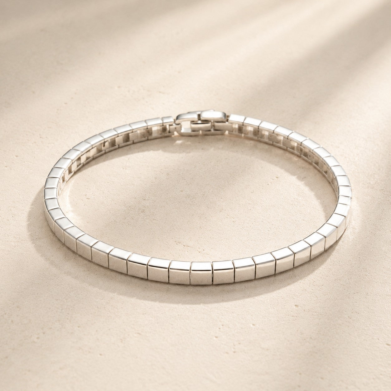 Flat lay view of minimalist silver square link mirror polish bracelet on beige background