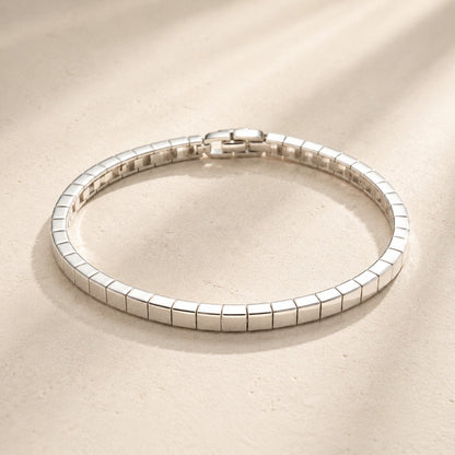 Flat lay view of minimalist silver square link mirror polish bracelet on beige background