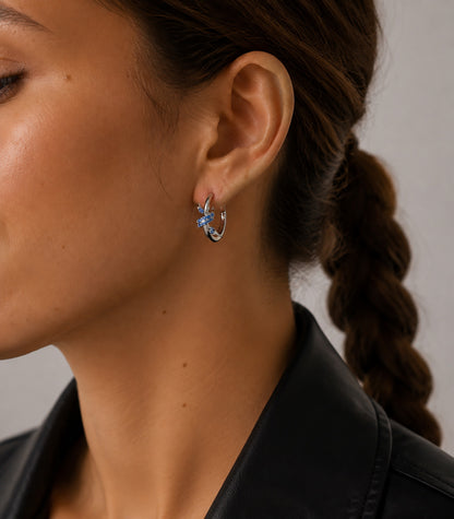 Elegant woman styling vintage knotted C-hoop earrings in sapphire blue and white gold-tone.