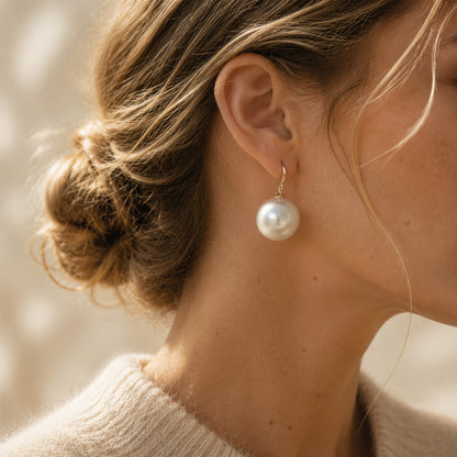 Close-up of an elegant woman styling bold 14K gold-plated french hook earrings with 19mm oversized pearls.