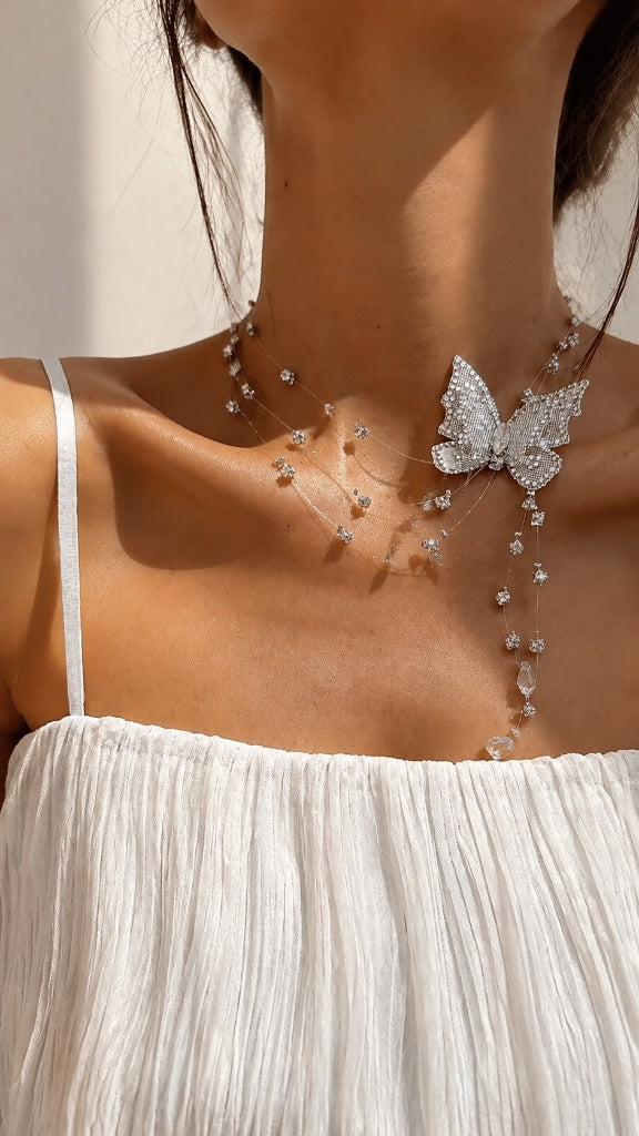 Close-up of an elegant woman showcasing an ethereal floating butterfly necklace made with illusion wire and sparkling cubic zirconia.