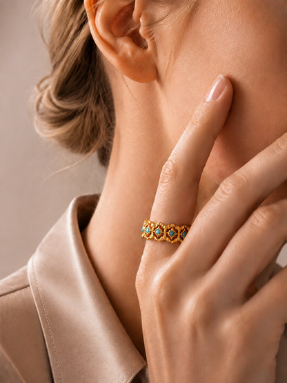 Close-up of an elegant woman's hand styling a vintage-inspired 18K gold-tone turquoise filigree ring.