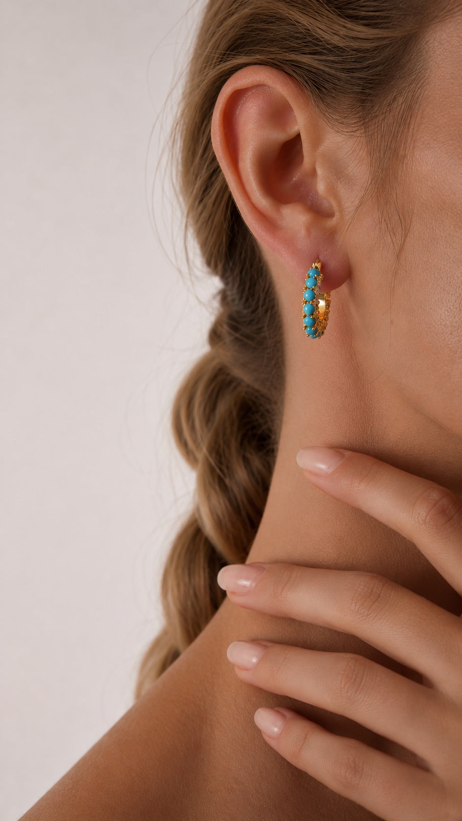 Side view close up of model with braided hair wearing 2cm gold turquoise bead huggie hoop earrings
