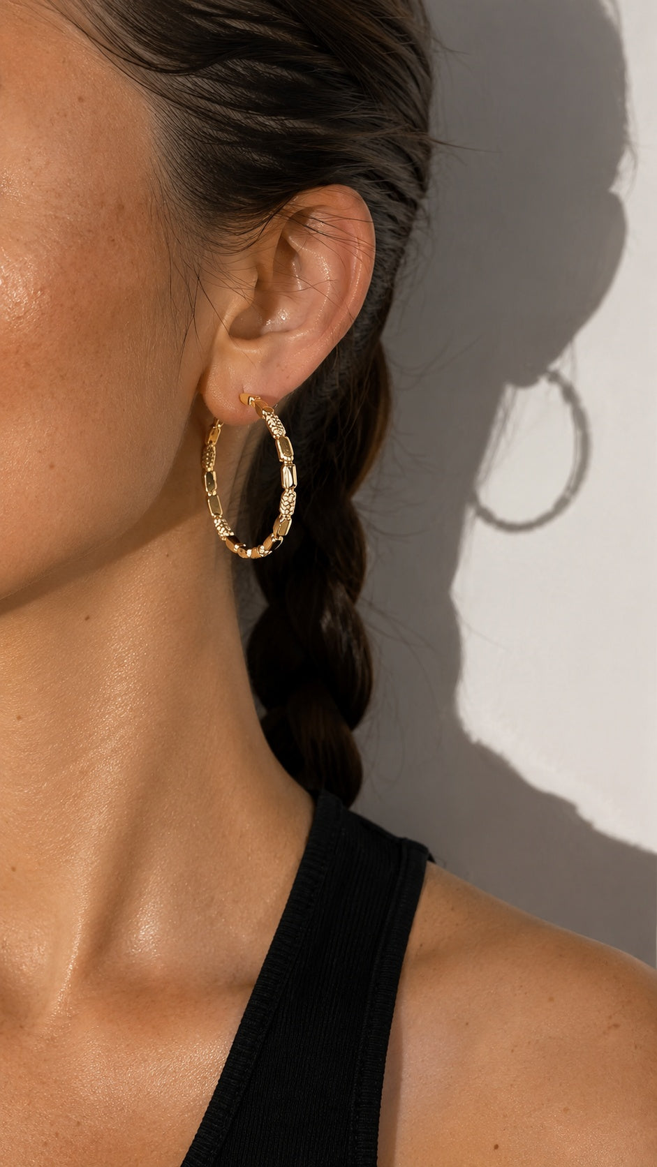 Side view close up of model wearing 3.8cm gold link hoop earrings black top
