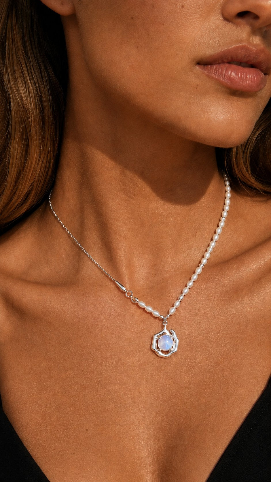 Close up of model wearing asymmetric freshwater pearl and silver chain necklace with iridescent opaline pendant