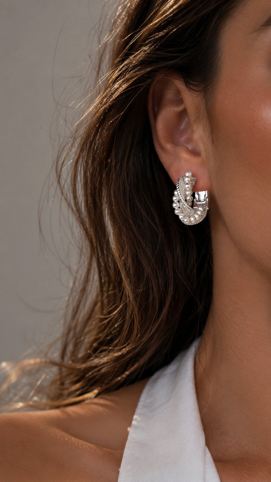 Side view close up of model wearing chunky twisted silver rope pearl hoop earrings with white top