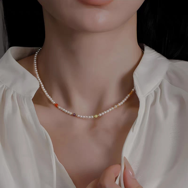 Model wearing dainty faux pearl choker necklace with colorful accent beads paired with white silk blouse