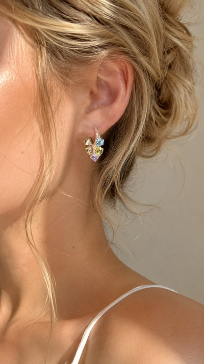 Side portrait shot of blonde model wearing colorful pastel sugar cube crystal dangle huggie earrings under soft sunlight