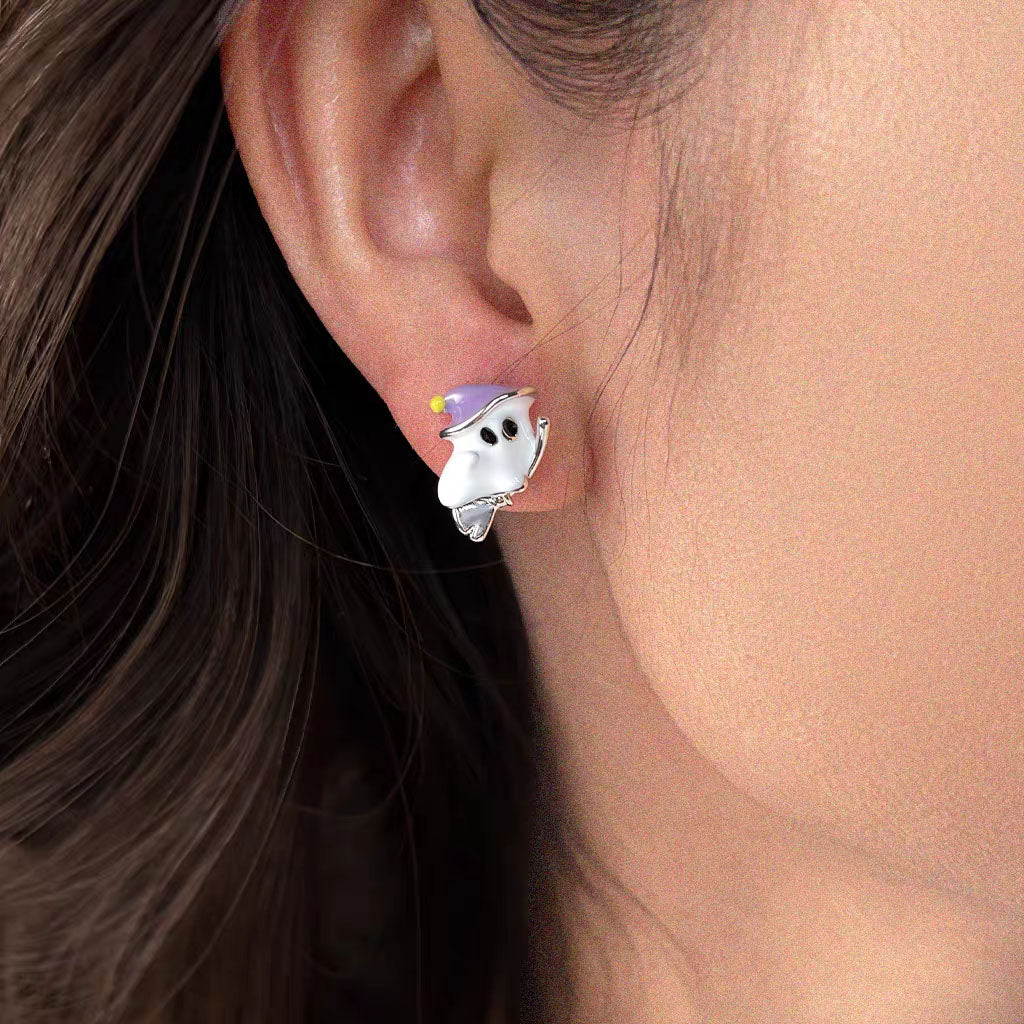 Close-up of model wearing cute flying ghost stud earring with purple witch hat on earlobe