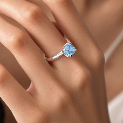 Model wearing solitaire glacier blue gemstone silver ring on index finger
