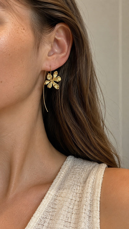 Side profile view of model with brown hair wearing long gold sculpted orchid flower drop earrings