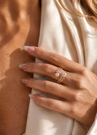 Close-up of an elegant woman's hand wearing a stunning 18K gold-tone twisted rope ring with two freshwater pearls.