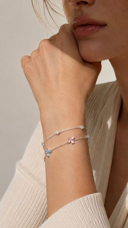 Close up of model rest hand wearing dainty pastel four-leaf flower double strand silver bracelet with cream sweater