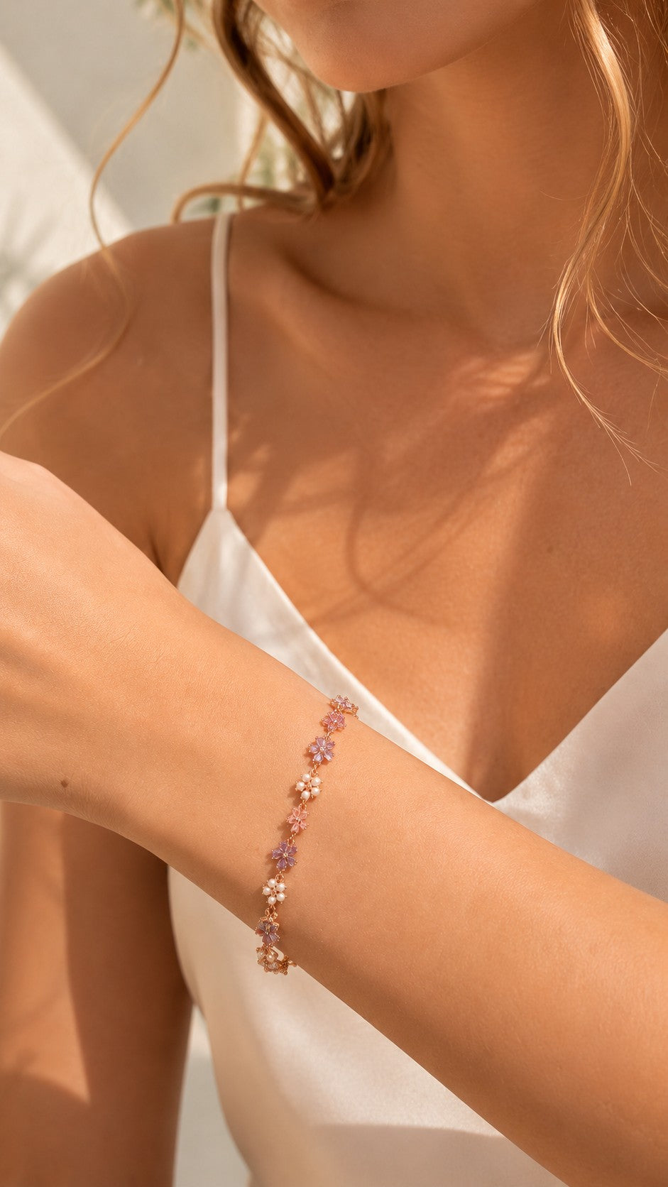 Close up of model wearing dainty rose gold lavender flower CZ bracelet with white silk dress
