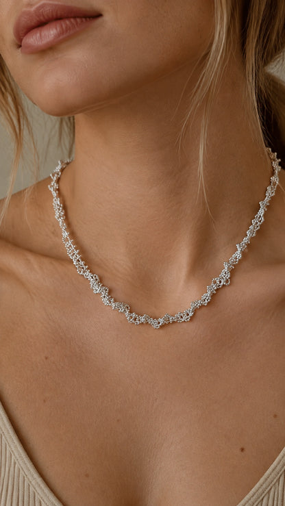 Model wearing single layer silver lace pattern short necklace highlighting cubic zirconia sparkle
