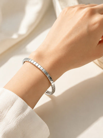 Model wrist close-up wearing silver mirror ice cube geometric block bracelet under soft sunlight