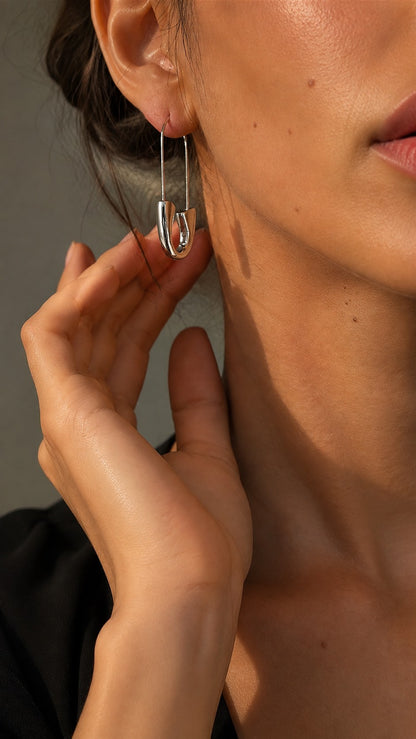 Side view of model wearing sculptural silver safety pin U-shape drop earring