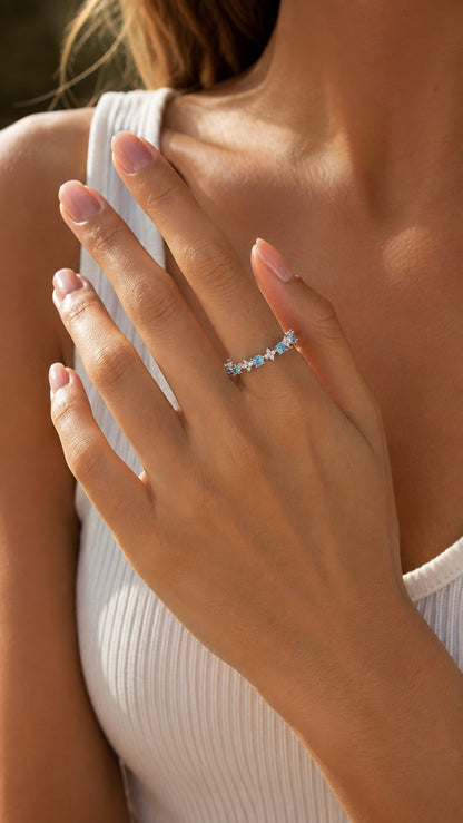 Side angle portrait of blonde model wearing aquamarine blue floral adjustable open ring with a ribbed white top