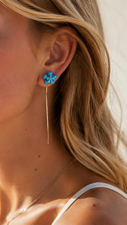 Blonde model with sun-kissed skin wearing turquoise flower gold threader chain earrings in golden hour light
