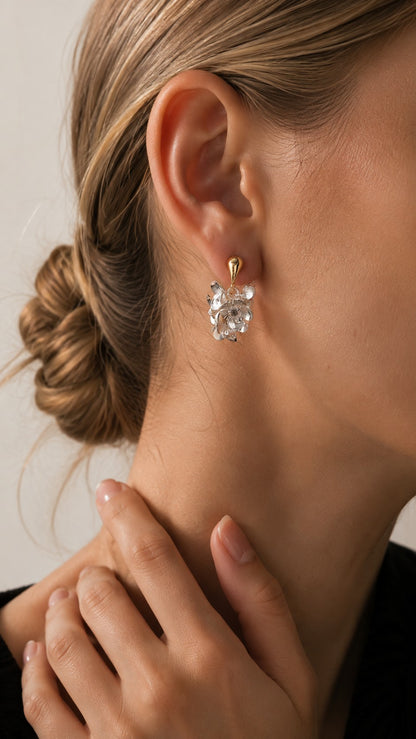Side profile close-up of model with bun touching neck, wearing silver flower drop earring